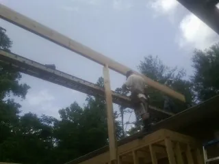 Carpenter setting a ridge beam over a new addition frame — Ice Dam Removal by Roofing Brothers in Falls Church