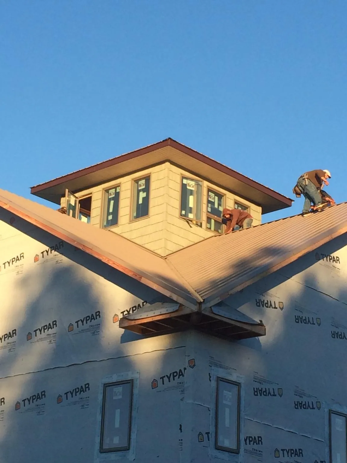Roofers working around a rooftop cupola on a new metal roof at sunset — Roof Waterproofing in Falls Church by Roofing Brothers